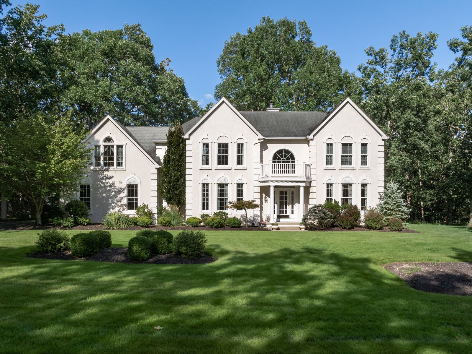 White colonial home with a columned entry and front lawn in Medford, NJ
