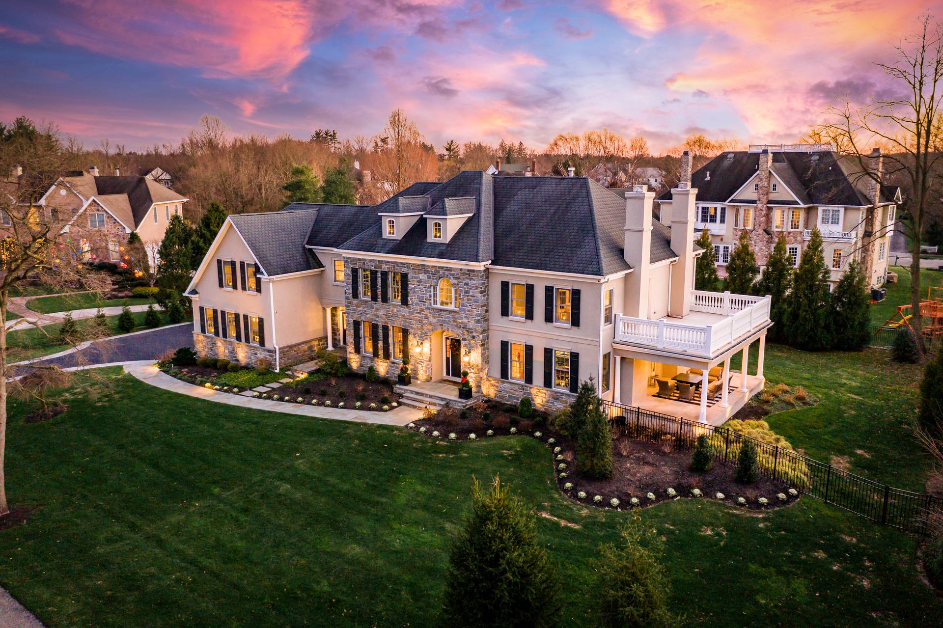 Twilight aerial of a stone-front colonial glowing at dusk, South Jersey